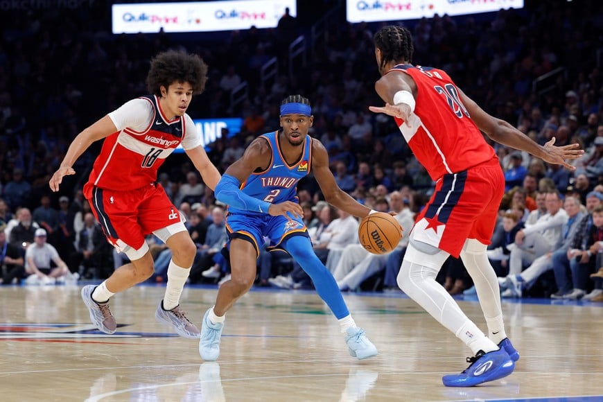 Oct 30, 2025; Oklahoma City, Oklahoma, USA; Oklahoma City Thunder guard Shai Gilgeous-Alexander (2) drives between Washington Wizards forward Kyshawn George (18) and center Alex Sarr (20) during the second half at Paycom Center. Mandatory Credit: Alonzo Adams-Imagn Images