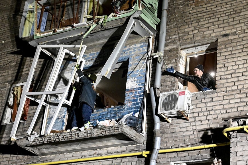 A rescuer and a resident work at the site of a damaged apartment building hit by a Russian drone strike, amid Russia's attack on Ukraine, in Zaporizhzhia, Ukraine February 24, 2026. REUTERS/Stringer