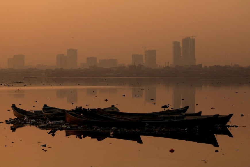 A bird sits on an anchored fishing boat, with buildings in the background amid smog and air pollution, in the morning, in Karachi, Pakistan, October 23, 2025. REUTERS/Akhtar Soomro 
     TPX IMAGES OF THE DAY