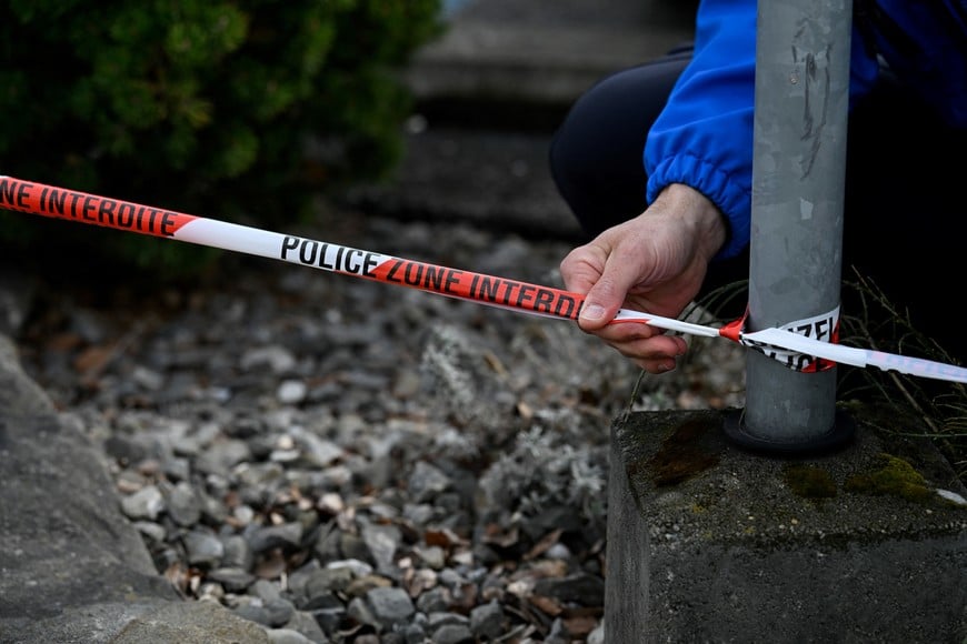 A police officer secures a cordon tape at the site of a deadly bus fire, in Kerzers, Switzerland, March 11, 2026. REUTERS/Romina Amato