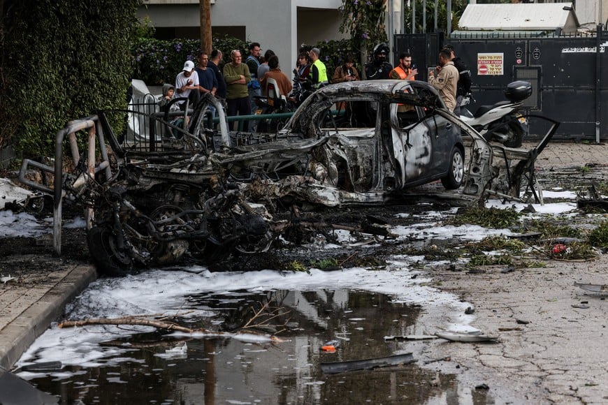 People gather near destroyed vehicles following an Iranian projectile strike, amid the U.S.-Israeli conflict with Iran, in central Israel, March 15, 2026. REUTERS/Tyrone Siu?