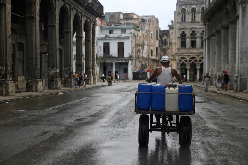 A man carries water tanks on a tricycle as Cuba reconnected its electrical grid across much of the island according to the Energy and Mines Ministry, following a nationwide blackout that left about 10 million people without electricity, in Havana, Cuba March 17, 2026. REUTERS/Norlys Perez