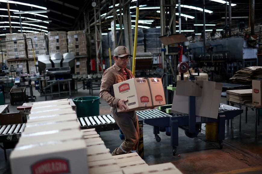 An employee moves boxes at Lumilagro’s factory, which now operates only one of its four assembly lines due to cheaper imported components and reduced demand, as Argentines face reduced consumer purchasing power under President Javier Milei’s austerity measures, in Tortuguitas, on the outskirts of Buenos Aires, Argentina, October 3, 2025. REUTERS/Agustin Marcarian  fabrica industria termos termo empleo oficios  metalurgia metalurgica vidrio plastico