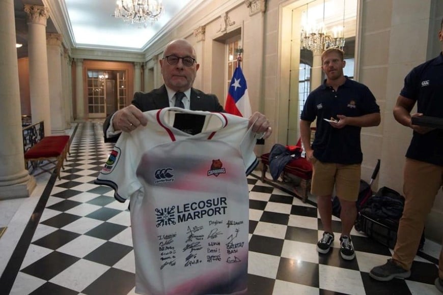 Jorge Faurie muestra con orgullo la camiseta de Capibaras firmada, ante la mirada de "Nacho" Gandini y el "Colo" Dogliani, capitán y subcapitán respectivamente de la franquicia del Litoral.