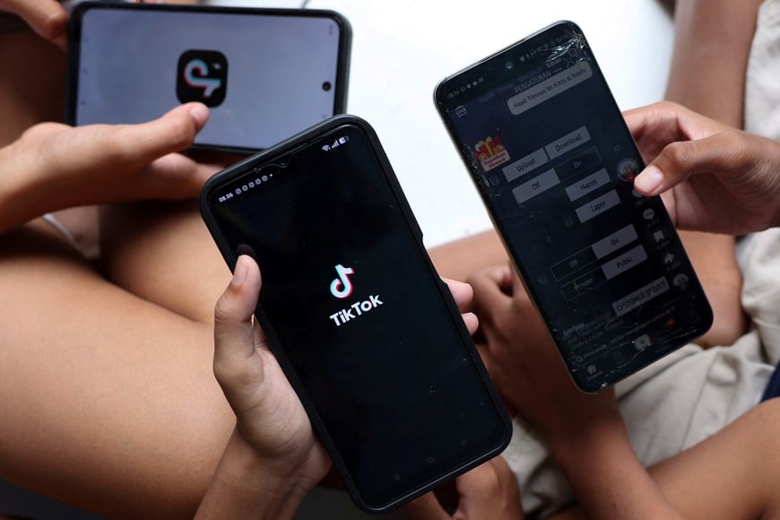 Affan Haritsah, 11, Daffa Ibnu Alkhalifi, 12, and Kevin Prince, 14, use TikTok on their phones, as Indonesia's communications and digital information ministry implements restrictions against "high-risk" social media platforms, including Facebook, TikTok, and Roblox, in Depok, on the outskirts of Jakarta, Indonesia, March 28, 2026. REUTERS/Ajeng Dinar Ulfiana