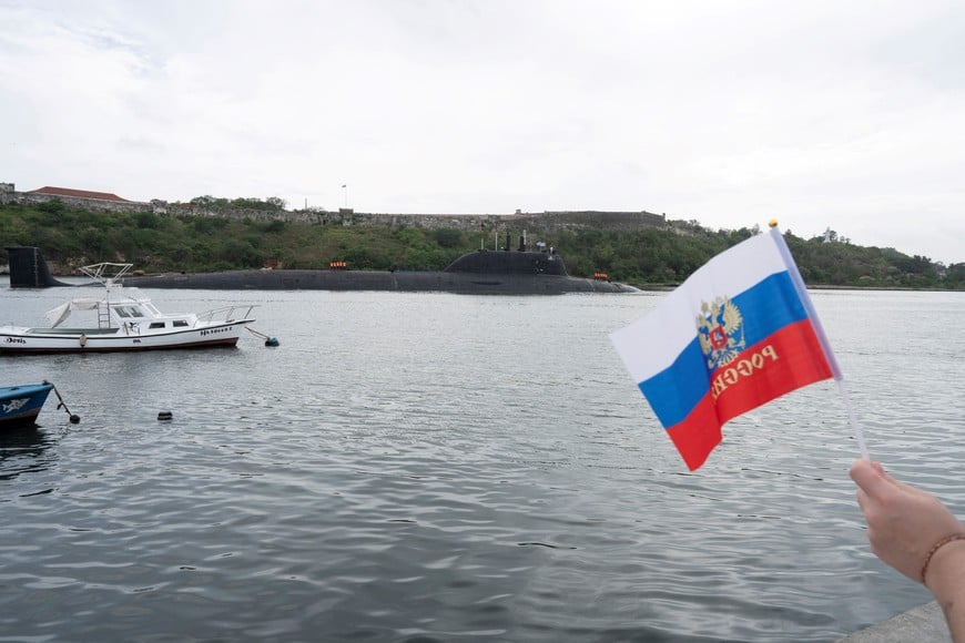 A member of the Russian community holds a flag as Russian nuclear-powered cruise missile submarine Kazan enters Havana’s bay, Cuba, June 12, 2024. REUTERS/Alexandre Meneghini