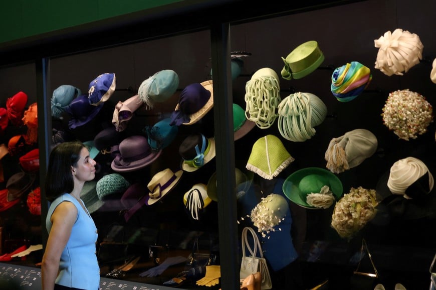 A Royal Collection Trust staff member poses beside hats which form part of "Queen Elizabeth II: Her Life in Style", an exhibition of clothing and outfits marking the centenary of the late queen’s birth, in The King’s Gallery at Buckingham Palace, London, Britain, April 9, 2026. REUTERS/Toby Melville