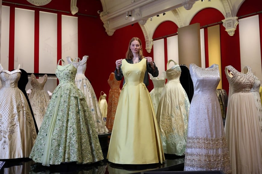 Royal Collection Trust exhibitions manager Laura Drew  poses with dresses in the evening wear of "Queen Elizabeth II: Her Life in Style", an exhibition of clothing and outfits marking the centenary of the late queen's birth, in The King's Gallery at Buckingham Palace, London, Britain, April 9, 2026. REUTERS/Toby Melville