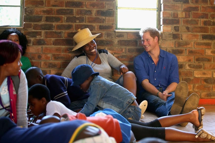 Prince Harry sits next to a volunteer who was laughing at his singing during a visit to a Mamohato Network Club for children living with HIV at St Paul Centre in Maseru, Lesotho, on December 9, 2014. Prince Harry was visiting Lesotho to see the work of his charity Sentebale which Sentebale provides healthcare and education to vulnerable children in Lesotho, Southern Africa. REUTERS/Pool/Chris Jackson (LESOTHO - Tags: HEALTH ROYALS SOCIETY) Maseru Lesotho principe Harry principe de inglaterra visita de caridad a Lesotho visita a enfermos con HIV