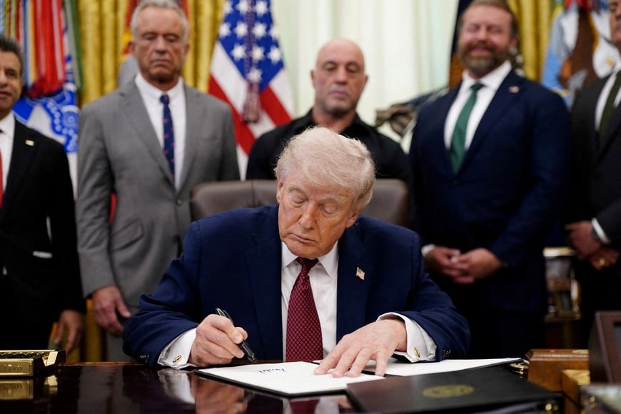 U.S. President Donald Trump signs an executive order encouraging more research into ibogaine, next to U.S. Health and Human Services (HHS) Secretary Robert F. Kennedy Jr., Joe Rogan, and Americans for Ibogaine CEO W. Bryan Hubbard, in the Oval Office of the White House in Washington, D.C., April 18, 2026. REUTERS/Nathan Howard REFILE - ADDS "W." TO "W. BRYAN HUBBARD".