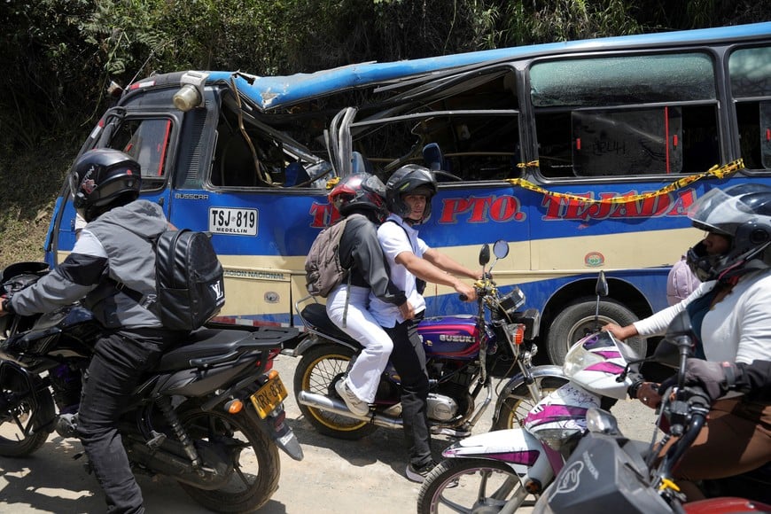 People pass by next to a destroyed vehicle after an attack with explosives that killed over a dozen people on the Pan-American Highway in the El Tunel area of Cajibio, Colombia April 26, 2026. REUTERS/Jair Coll