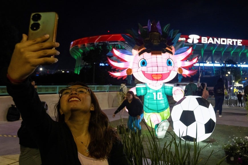A fan takes a selfie with her cellphone outside Azteca Stadium, officially renamed Estadio Banorte, on the day of a friendly match between the national teams of Mexico and Portugal held to mark the stadium’s inauguration, as Mexico prepares for the 2026 FIFA World Cup co-hosted by the United States, Canada and Mexico, in Mexico City, Mexico, March 28, 2026. REUTERS/Quetzalli Nicte-Ha