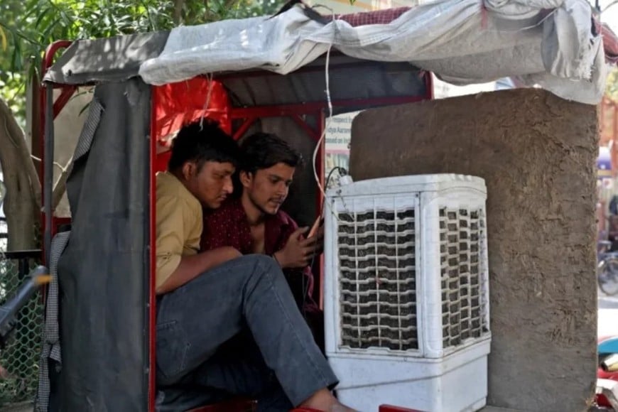 Hombres se sientan frente a un enfriador de aire en un rickshaw eléctrico en Delhi el 23 de abril de 2026.