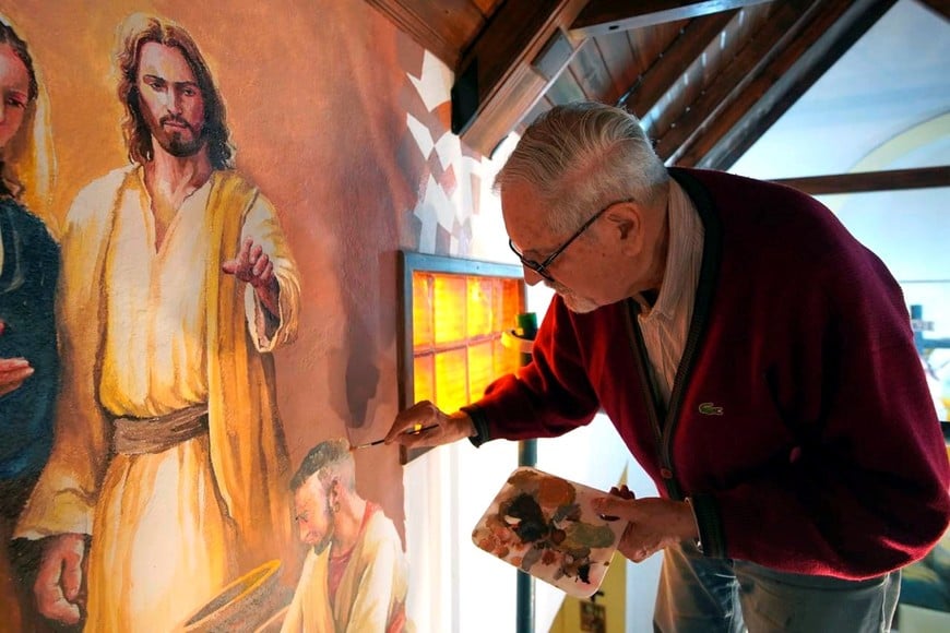 Lazzarini pinta los murales que transforman la cuasi parroquia Santa María. Foto: Fernando Nicola