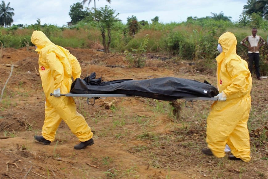Health workers carry the body of an Ebola virus victim in the Waterloo district of Freetown, October 21, 2014. Authorities in Sierra Leone imposed a curfew in the eastern town of Koidu on Tuesday after a dispute between youth and police over a suspected case of Ebola degenerated into gunfire and rioting, officials said. Picture taken October 21, 2014. REUTERS/Josephus Olu-Mamma (SIERRA LEONE - Tags: DISASTER HEALTH POLITICS CIVIL UNREST) sierra leona  sierra leona traslado muerto por el ebola epidemia mundial de ebola muertes muertos cuerpos cadaveres