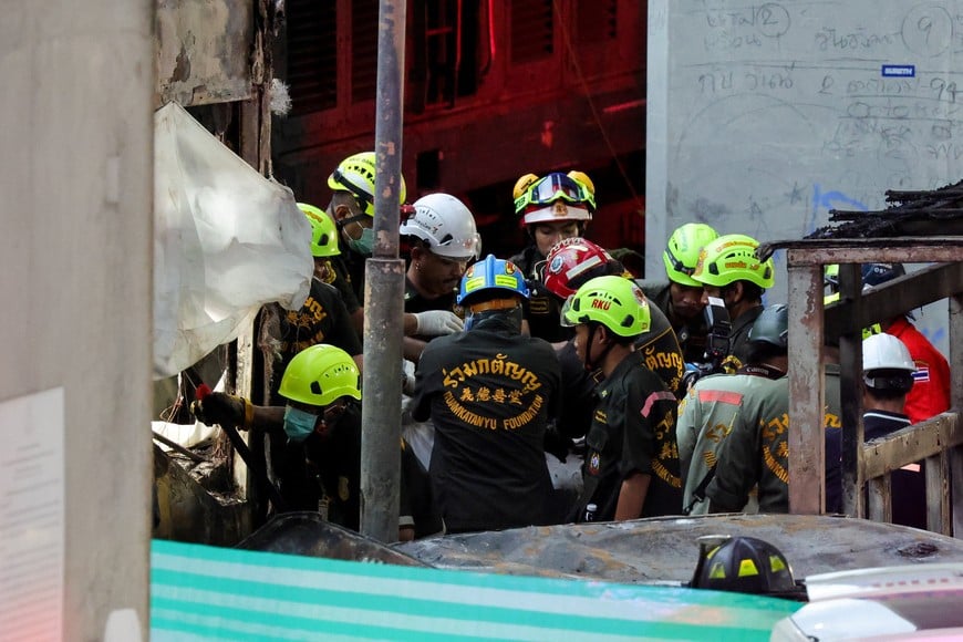 Emergency services members carry a dead body at a site where a train collided with a bus and several cars on Asok-Din Daeng Road, causing several casualties, in Bangkok, Thailand, May 16, 2026. REUTERS/Athit Perawongmetha