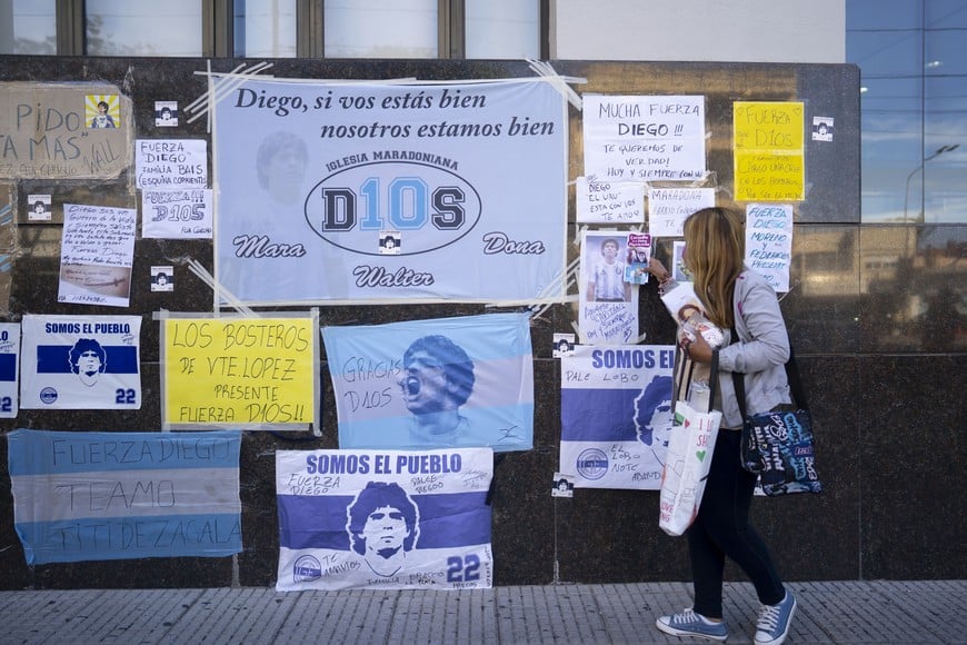 (201104) -- VICENTE LOPEZ, 4 noviembre, 2020 (Xinhua) -- Una mujer coloca una estampa religiosa junto a carteles y mensajes de apoyo pegados en un muro frente a la Clínica Olivos, donde el martes fue operado el entrenador argentino de fútbol, Diego Armando Maradona, en la localidad de Vicente López, Argentina, el 4 de noviembre de 2020. El ex astro argentino de fútbol Diego Armando Maradona experimentó el miércoles una "asombrosa" recuperación tras ser operado de un hematoma en la superficie cerebral, afirmó su médico personal, Leopoldo Luque. (Xinhua/Martín Zabala) (mz) (jg) (da) (vf) (ce)