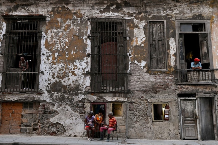 People eat outside of a small cafeteria while neighbors look out from a balcony, as Cuba's state-run economy has descended into a full-blown crisis after the administration of U.S. President Donald Trump hardened sanctions and cut off the Caribbean nation's oil supply, in Havana, Cuba February 21, 2026. REUTERS/Norlys Perez TPX IMAGES OF THE DAY