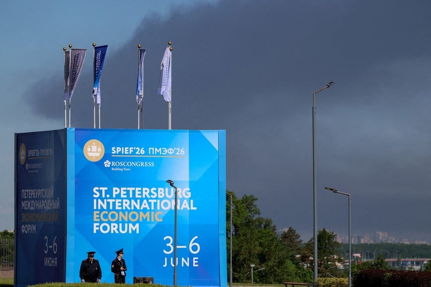 FILE PHOTO: Police officers stand in front of a banner and flags with the logo of the St. Petersburg International Economic Forum (SPIEF) as heavy smoke billows in the background after Ukrainian drones hit infrastructure, according to local authorities, in St Petersburg, Russia June 3, 2026. REUTERS/Stringer/File Photo