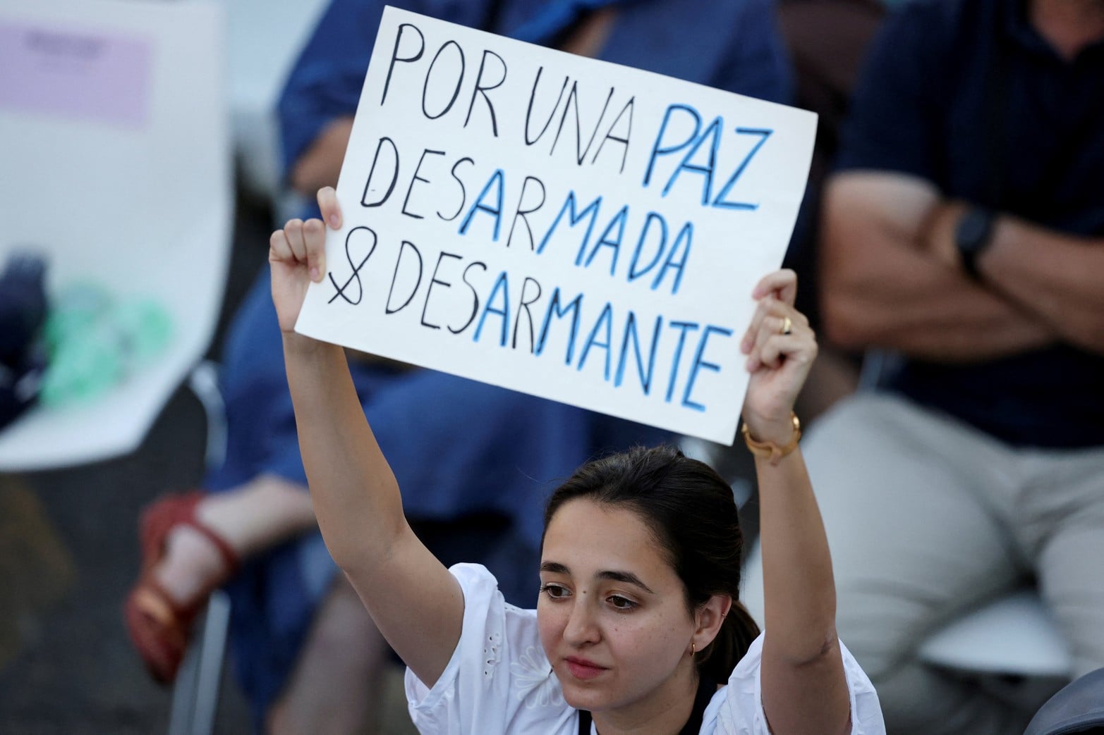 Una mujer sostiene un cartel que dice: "Por una paz desarmada y desarmante" mientras asiste a una vigilia de oración oficiada por el Papa León XIV.