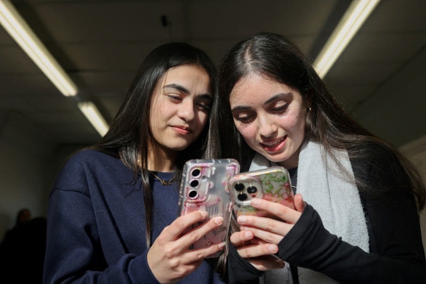 FILE PHOTO: Students Dua, 16 and Awand, 17, from Ricards Lodge High School in Wimbledon pose holding their mobile phones during an interview and discussion with Reuters about their thoughts on a social media ban for under 16s, in London, Britain, February 23, 2026, REUTERS/Katie Collins/File Photo