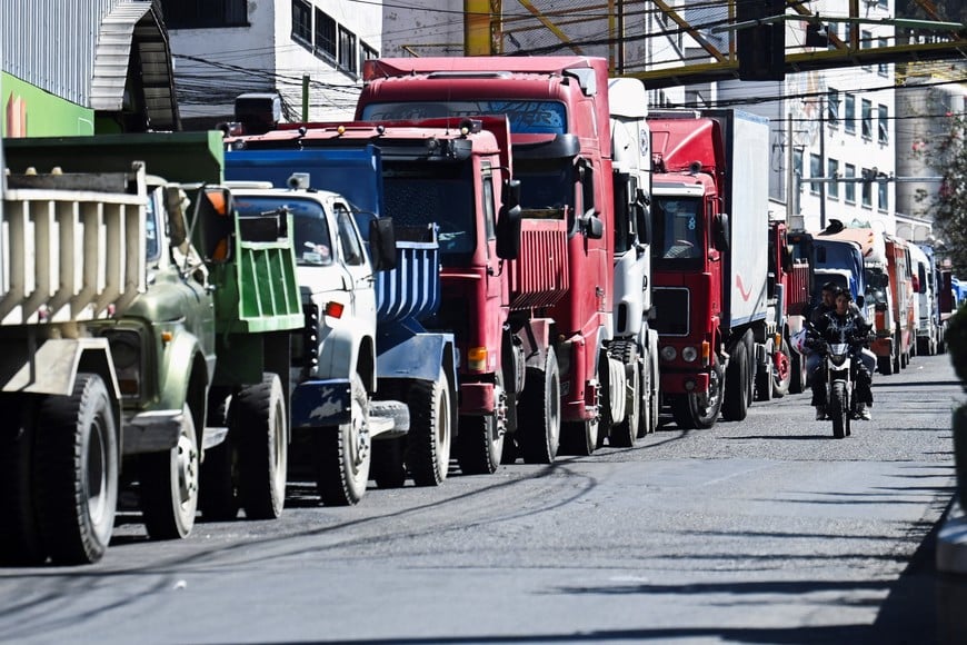 Two people on a motorcycle ride past trucks waiting in line, as protests have caused supply chain disruptions in the cities of La Paz and El Alto, leading to severe shortages of food, fuel and medicine, in La Paz, Bolivia, June 15, 2026. REUTERS/Claudia Morales