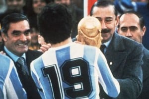 El entonces presidente de facto de Argentina, general Jorge Rafael Videla, le entrega la Copa del Mundo de 1978 al capitán argentino Daniel Passarella. Completa la imagen, sonriente, el almirante Eduardo Emilio Massera.