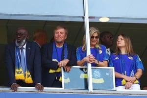 Los reyes Guillermo Alejandro y Máxima junto a una de sus hijas, los tres con la camiseta de Curazao. REUTERS