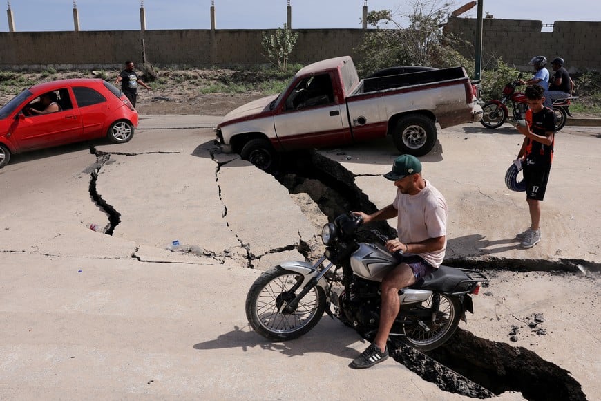 A man sits on a bike on a damaged road after earthquakes hit the country, in La Guaira, Venezuela, June 25, 2026. REUTERS/Gaby Oraa     TPX IMAGES OF THE DAY