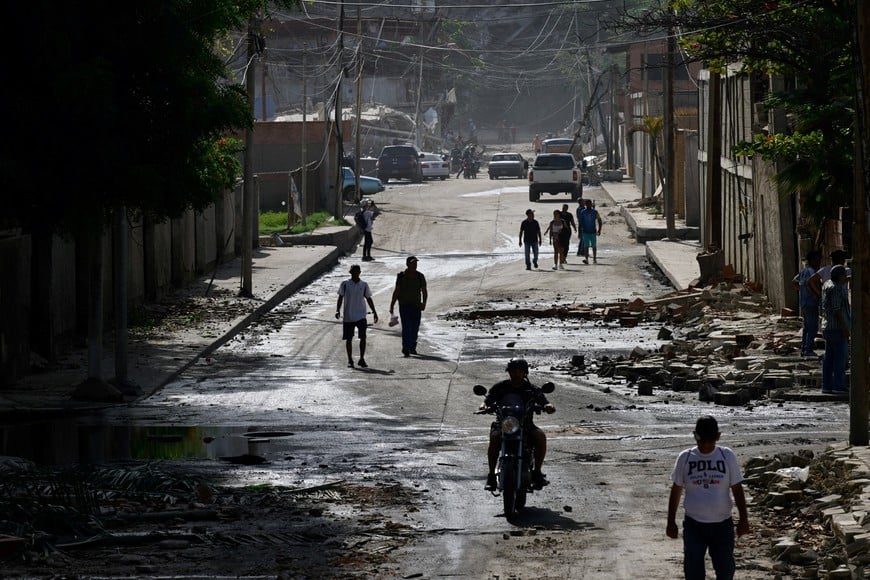 People walk past the rubble of damaged buildings in the aftermath of earthquakes in La Guaira, Venezuela, June 25, 2026. REUTERS/Maxwell Briceno