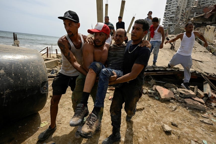 People carry an injured man, in the aftermath of earthquakes in La Guaira, Venezuela, June 25, 2026. REUTERS/Maxwell Briceno