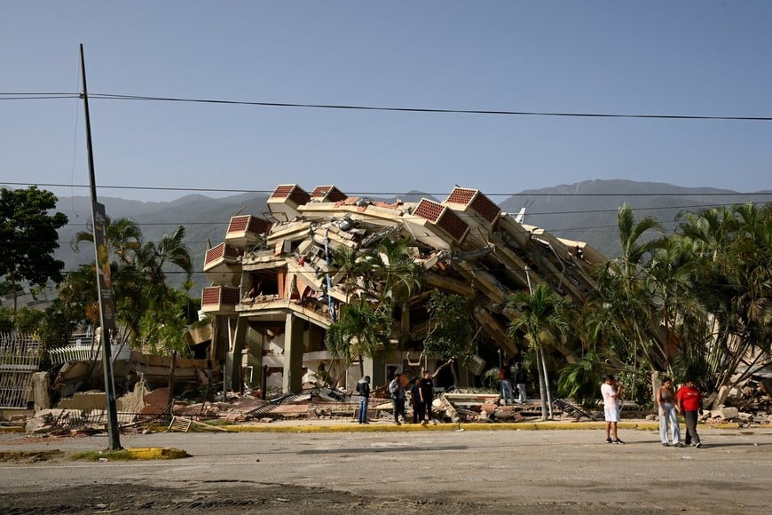 People gather outdoors near a collapsed building after earthquakes hit the country, in La Guaira, Venezuela, June 26, 2026. REUTERS/Maxwell Briceno