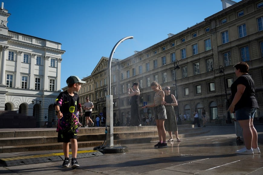 (260628) -- VARSOVIA, 28 junio, 2026 (Xinhua) -- Imagen del 27 de junio de 2026 de personas refrescándose bajo un dispositivo de nebulización pública, en Varsovia, Polonia. El Instituto Polaco de Meteorología y Gestión del Agua emitió su alerta máxima por calor, de nivel 3, desde la mañana del sábado hasta la noche del lunes. Se espera que el pico de la ola de calor se alcance el domingo, cuando las temperaturas en algunas regiones podrían llegar hasta los 42 grados Celsius, según el servicio meteorológico. (Xinhua/Jaap Arriens) (da) (ah)