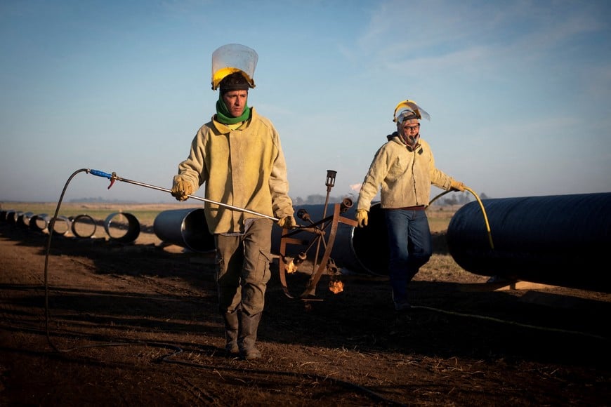 FILE PHOTO: Workers walk during the construction of the Nestor Kirchner gas pipeline, which first stage was inaugurated on Sunday to transport natural gas from the Vaca Muerta formation in western Argentina to the province of Santa Fe, passing through the province of Buenos Aires, in Macachin, La Pampa, Argentina April 26, 2023. REUTERS/Martin Cossarini/File Photo
