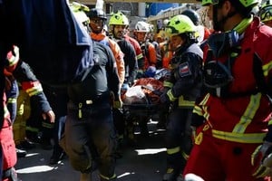 Hernán Gil, de 43 años, es trasladado por rescatistas internacionales (entre ellos, varios chilenos) en una camilla. Logró sobrevivir debajo de los escombros de un edificio en Catia La Mar, La Guaira, en una operación de salvamento que se extendió por tres días.