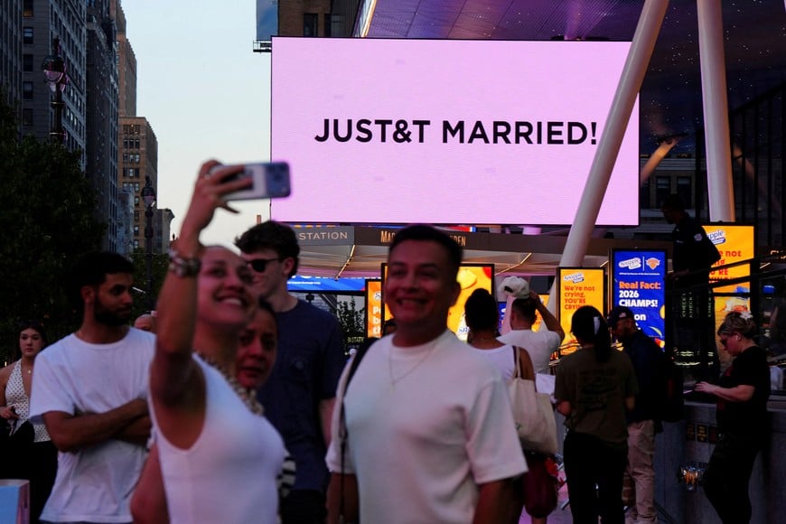 People take selfies next to a screen displaying a message referencing singer Taylor Swift and National Football League (NFL) player Travis Kelce outside Madison Square Garden, the venue for their wedding celebrations, in New York, U.S., July 3, 2026. REUTERS/Angelina Katsanis