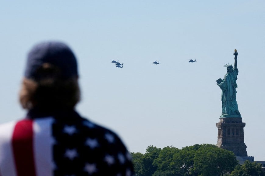 A person watches as helicopters perform a flyover near the Statue of Liberty during the Sail 250 parade of ships in New York Harbor as the United States celebrates its 250th anniversary on Independence Day, in Jersey City, New Jersey, U.S., July 4, 2026. REUTERS/Adam Gray