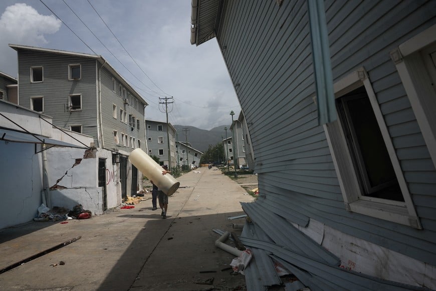 A man carries an item, near buildings damaged in the June 24 earthquakes, in La Guaira, Venezuela, July 5, 2026. REUTERS/Pablo Sanhueza