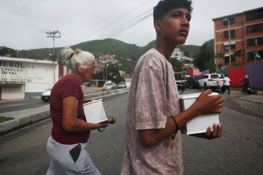 Zuleima Alvarado and Samuel Martinez walk while carrying the urns containing the remains of their relatives in the aftermath of the June 24 earthquakes, in La Guaira, Venezuela, July 5, 2026. REUTERS/Pablo Sanhueza