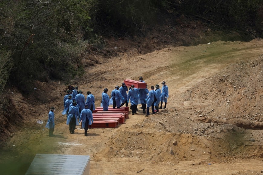 Workers carry a coffin of an earthquake victim, next to other coffins at La Esperanza Cemetery in the aftermath of the June 24 earthquakes, in La Guaira, Venezuela, July 6, 2026. REUTERS/Adriano Machado TPX IMAGES OF THE DAY