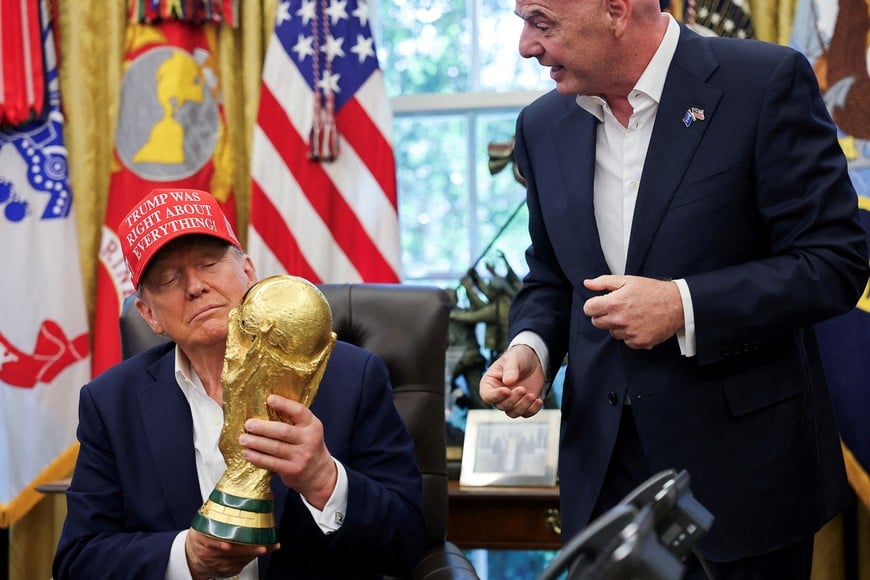 FILE PHOTO: U.S. President Donald Trump holds the FIFA World Cup Trophy, as he makes an announcement on the 2026 FIFA World Cup, as FIFA president Gianni Infantino stands next to him, in the Oval Office at the White House in Washington, D.C., U.S., August 22, 2025. REUTERS/Jonathan Ernst/File Photo