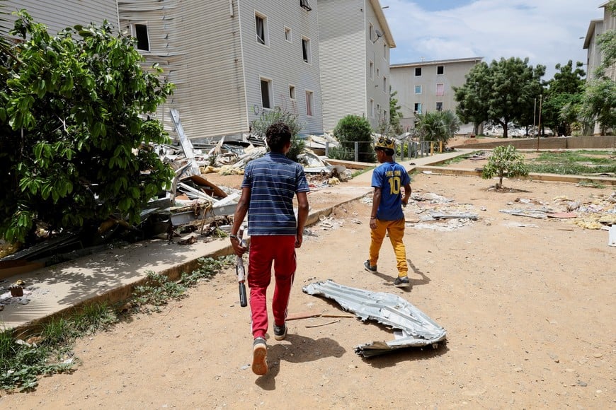 Children play with toy guns as they walk among debris scattered outside of damaged buildings, in the aftermath of the June 24 earthquakes in La Guaira, Venezuela, July 6, 2026. REUTERS/Ricardo Arduengo