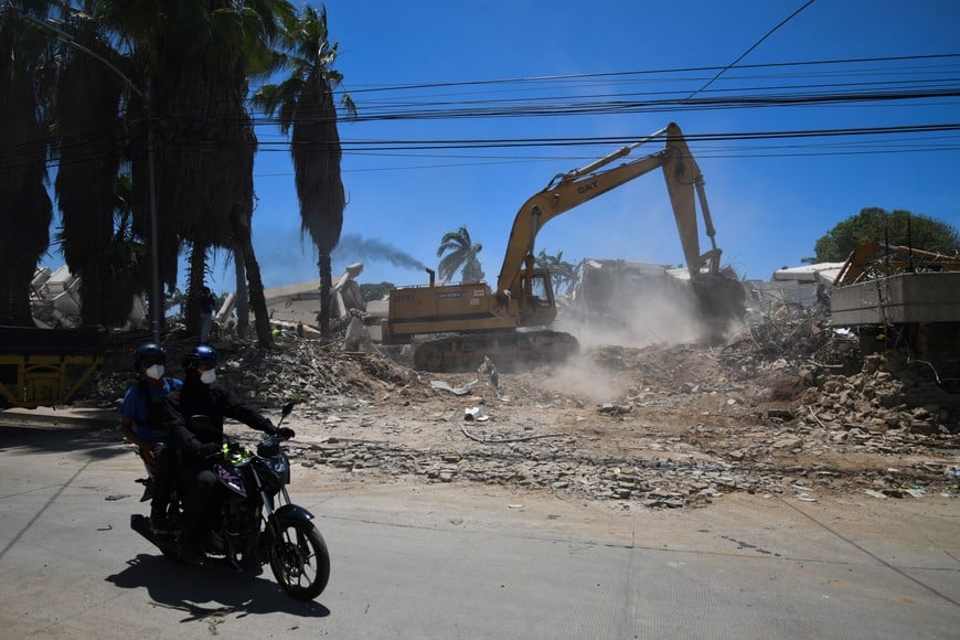 (260707) -- LA GUAIRA, 7 julio, 2026 (Xinhua) -- Personas circulan en motocicleta frente a maquinaria pesada que realiza tareas de remoción de escombros en un edificio colapsado luego de que se registraran dos terremotos, en Caraballeda, estado La Guaira, Venezuela, el 7 de julio de 2026. La cifra de fallecidos por los fuertes sismos registrados el pasado 24 de junio en Venezuela ascendió a 3.685, mientras que el número de heridos se mantuvo en 16.740, según el balance oficial divulgado el martes por el presidente de la Asamblea Nacional, Jorge Rodríguez. (Xinhua/Marcos Salgado) (ms) (jg) (ra) (vf)
