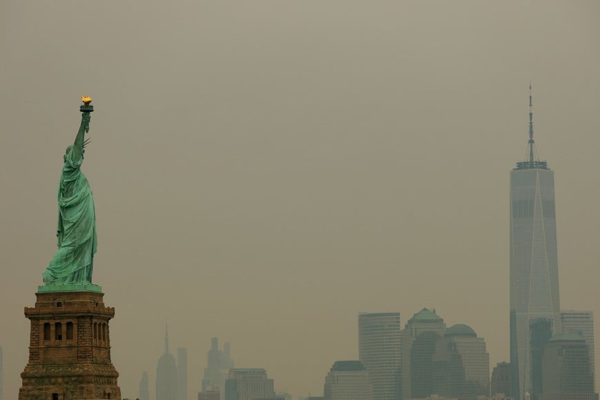 The Statue of Liberty in Jersey City, New Jersey, and the One World Trade Center tower in New York City are seen through a cover of wildfire smoke from New York Harbor, U.S., July 16, 2026. REUTERS/Mike Segar
