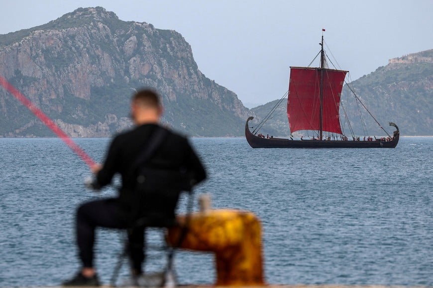A man fishes as a replica of an ancient warship is seen in the background, during the filming of The Odyssey, the latest project from director Christopher Nolan, in the town of Pylos, Greece, March 16, 2025. REUTERS/Louisa Gouliamaki TPX IMAGES OF THE DAY