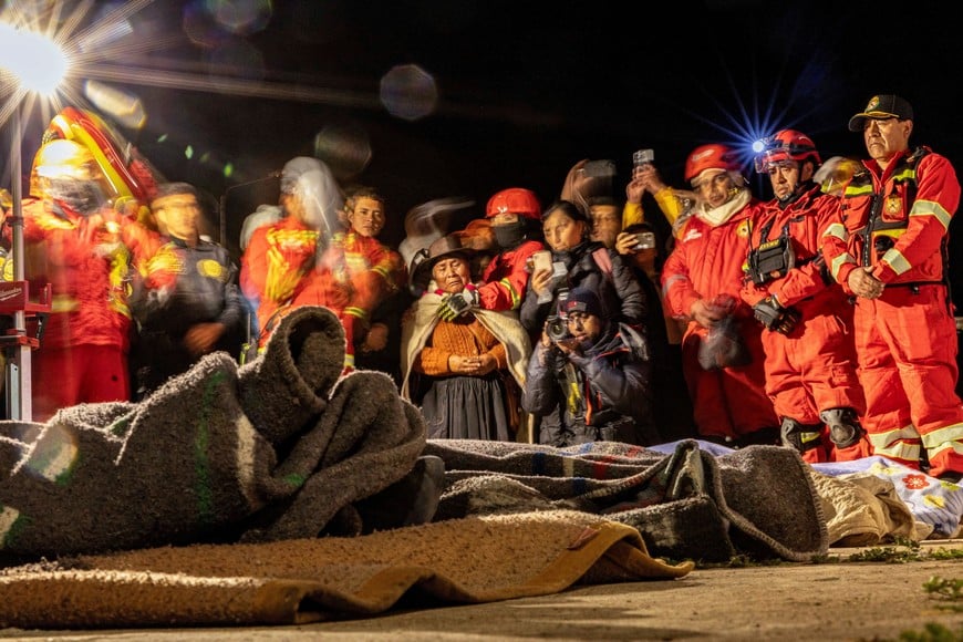 People pray next to the bodies of four victims of the earthquake of magnitude 5.6 that struck Central Peru on Saturday, in Chupuro, Peru, July 19, 2026. Picture taken with a long exposure. REUTERS/Yershon Vilca