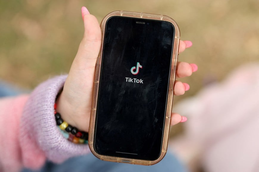 FILE PHOTO: A girl poses while opening the TikTok app on her phone in Sydney, Australia, November 22, 2025. REUTERS/Hollie Adams/File Photo