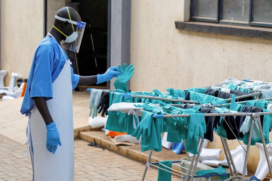 FILE PHOTO: A Ugandan worker collects a rubber glove from the airing line during a visit by the Director-General of the World Health Organisation (WHO) Tedros Adhanom Ghebreyesus at the Mulago National Referral Hospital Isolation Unit, as aid agencies intensify efforts to contain a new Ebola outbreak involving the Bundibugyo Virus, in Mulago suburb, of Kampala, Uganda, June 8, 2026. REUTERS/ Abubaker Lubowa/File Photo