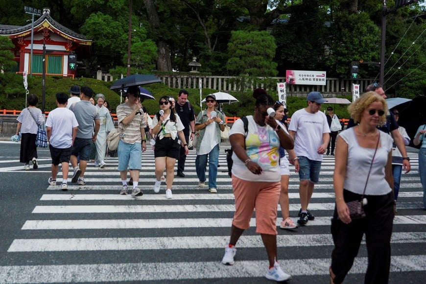 People use portable fans to cool themselves on the street as the Japanese government issued a heatstroke alert in Tokyo and other prefectures due to a heatwave, in Kyoto, western Japan July 23, 2026. REUTERS/Fred Mery