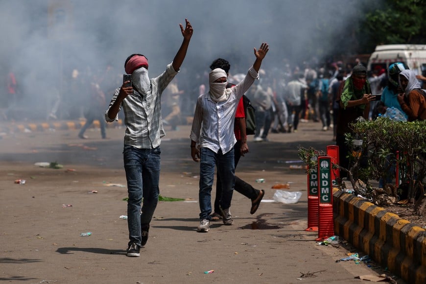 Masked people walk near plumes of tear gas as supporters of India's Cockroach Janta Party demonstrate demanding the resignation of Education Minister Dharmendra Pradhan over exam paper leaks, in New Delhi, India, 25 July, 2026. Pradhan announced his resignation later on Saturday. REUTERS/Anushree Fadnavis